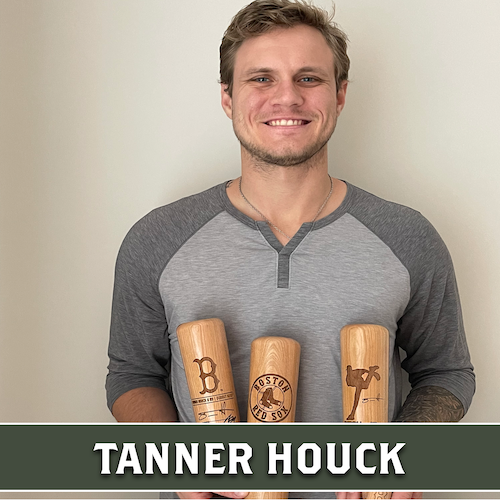 Tanner Houck smiling and holding three wooden Dugout Mugs baseball bat mugs with different engraved designs.